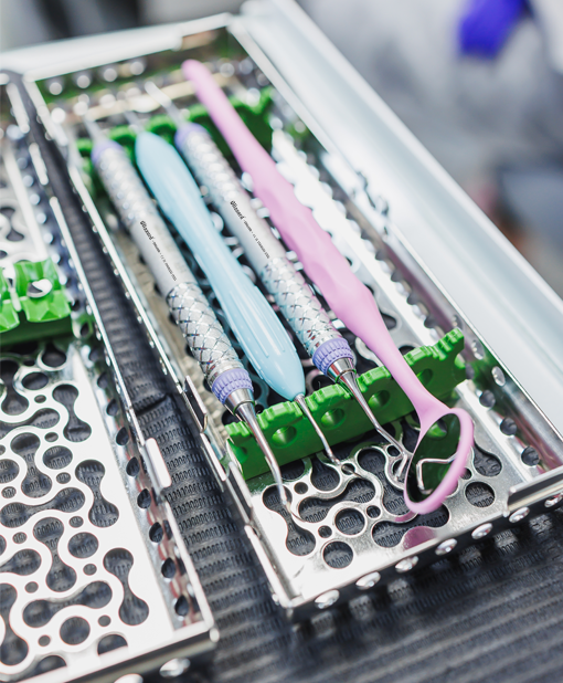 Set of dental instruments arranged in a sterilization tray with colorful silicone grips